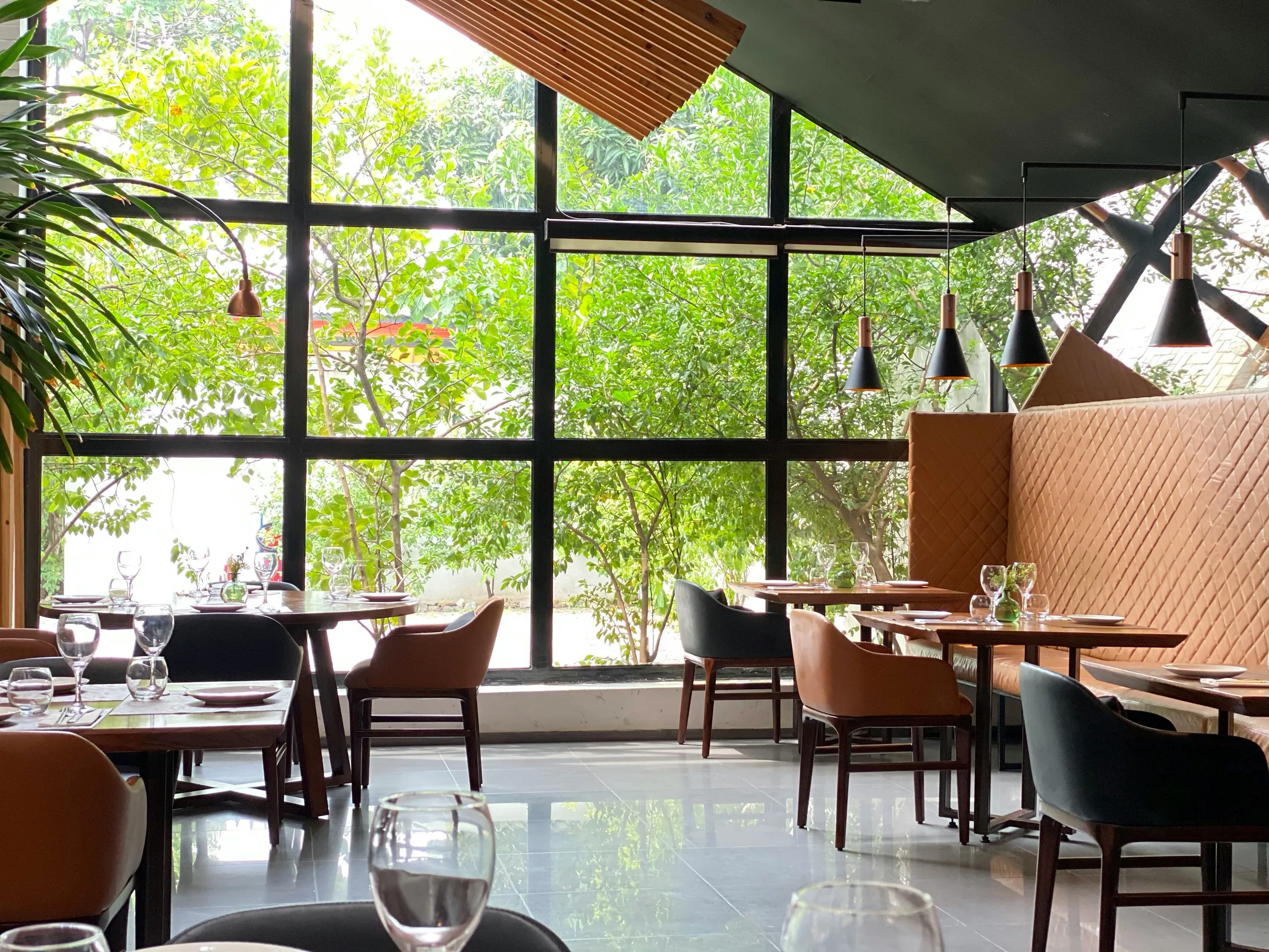 Interior tipo loft del restaurante con grandes cristaleras y vegetación al otro lado de la ventana