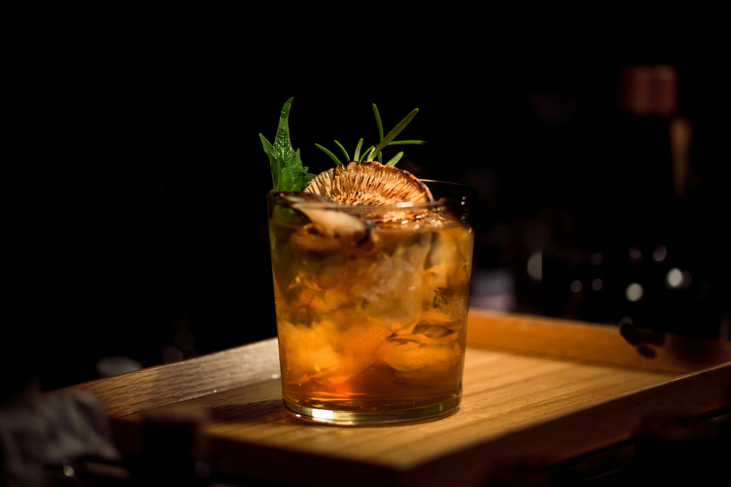 Estanterías de madera con botellas bajo la cálida luz del bar